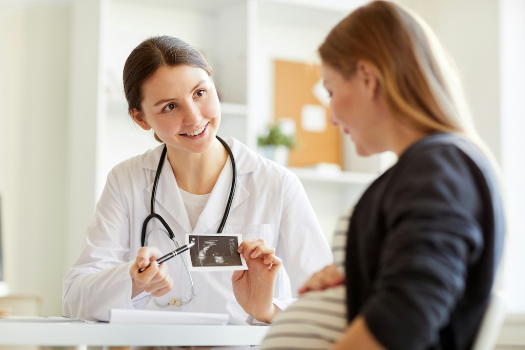 A healthcare professional showing a woman details of her baby scan.