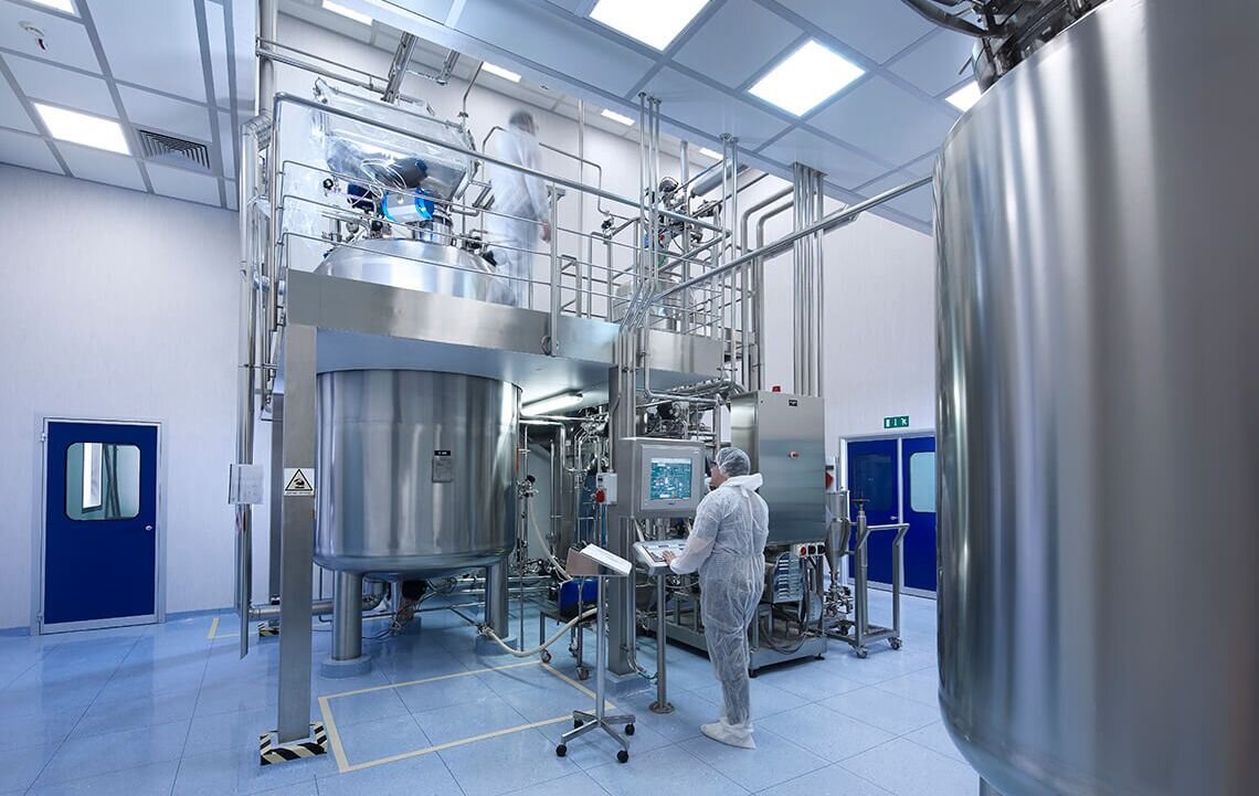 The inside of an IBSA factory, with a worker in white overalls inspecting a computer terminal.